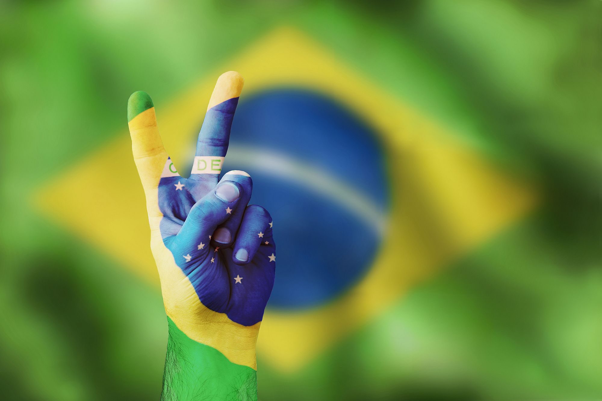 V as in victory. The Brazilian flag on the background