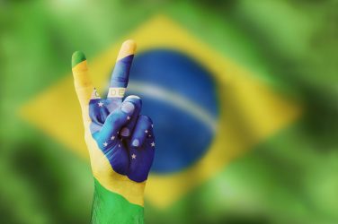 V as in victory. The Brazilian flag on the background