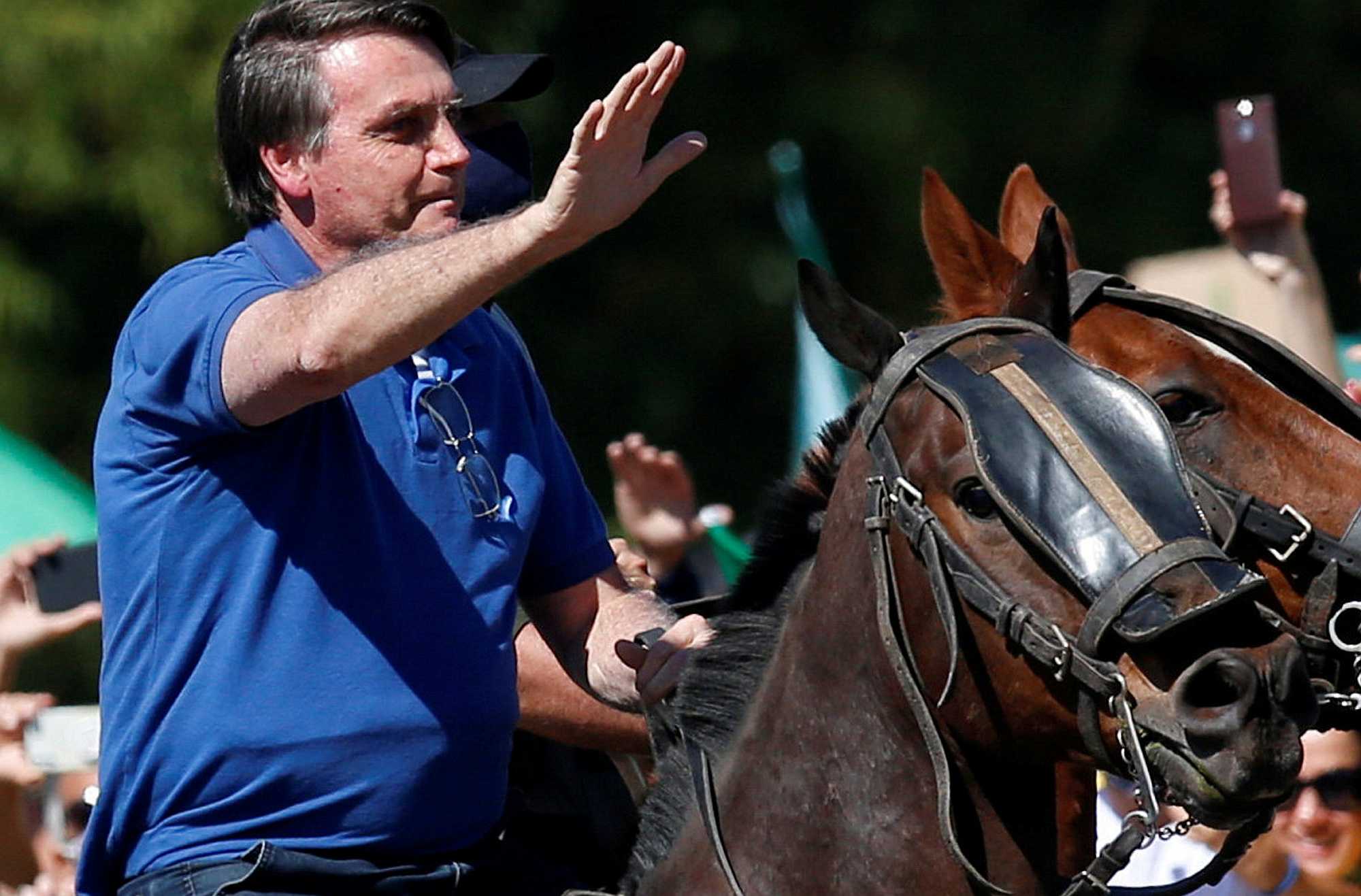 Brazilian president, Jair Bolsonaro, rides a horse while meeting fans.