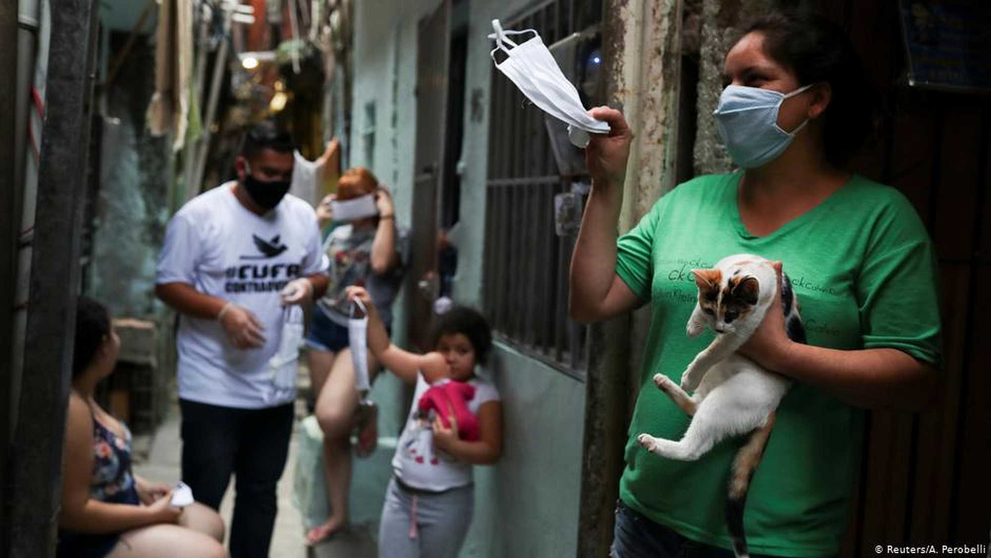 A woman in a favela in São Paulo holds up a facemask (Reuters/A. Perobelli)