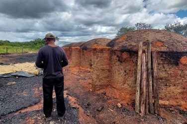 A charcoal producer poses in front of the charcoal kilns he works at, in Brazil. Image: Thomson Reuters Foundation/Fabio Teixeira
