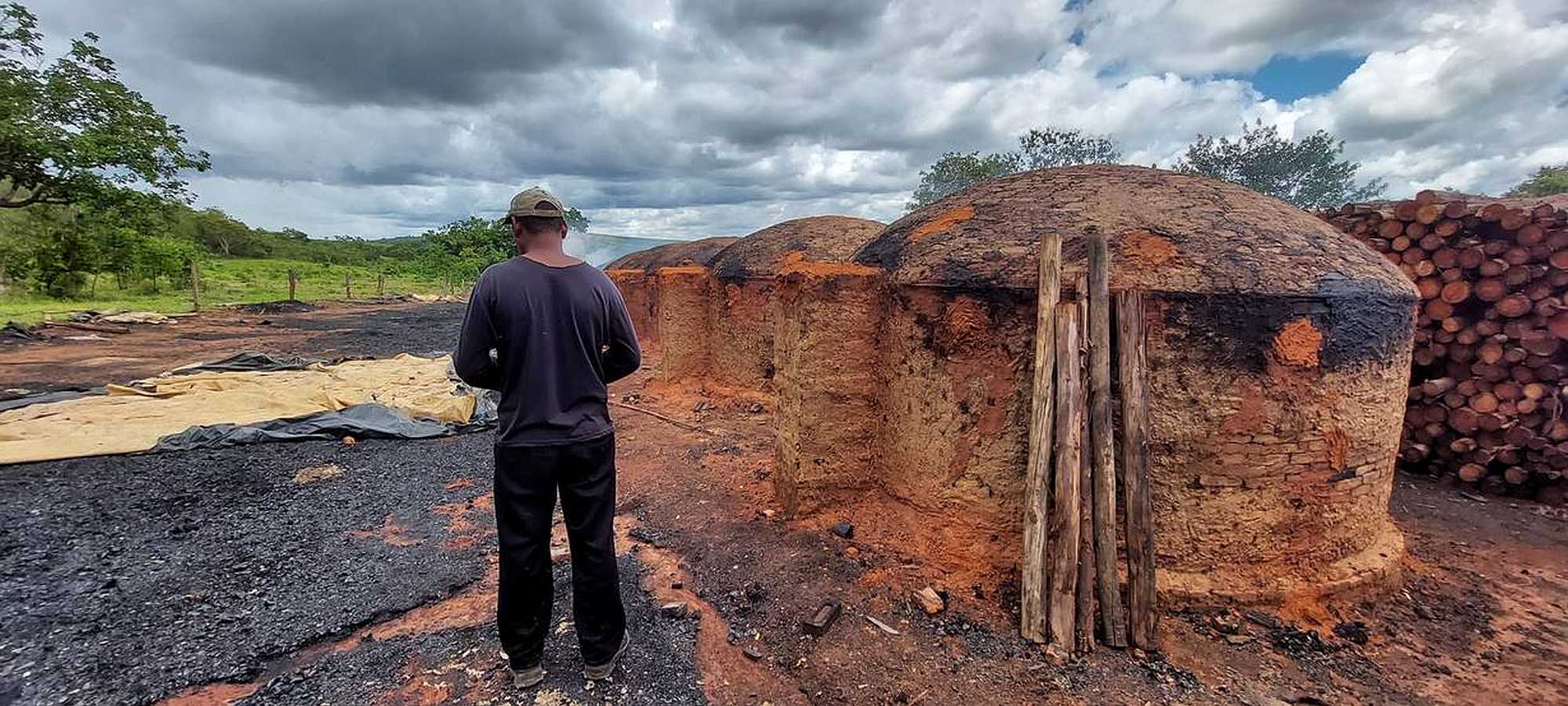 A charcoal producer poses in front of the charcoal kilns he works at, in Brazil. Image: Thomson Reuters Foundation/Fabio Teixeira